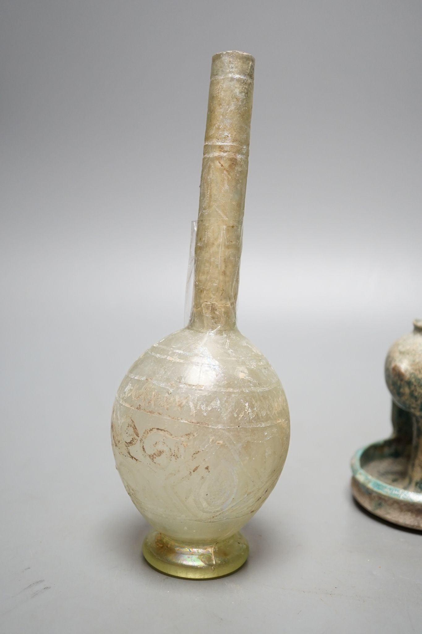 A Kashan oil lamp, 13th/14th century, and an early Islamic glass bottle., Bottle 22 cms high.